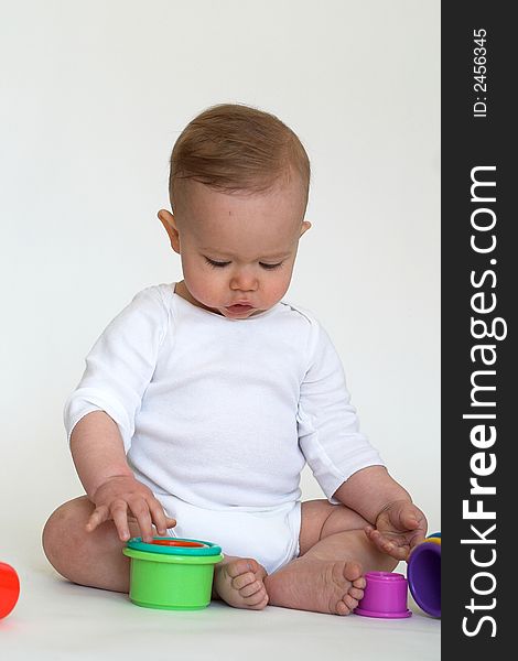 Image of an adorable baby playing with colorful stacking cups. Image of an adorable baby playing with colorful stacking cups