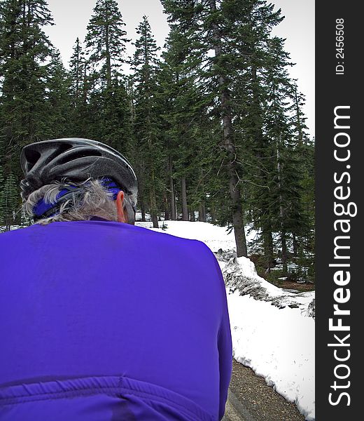 Road cyclist in purple on mountain road in snow. Road cyclist in purple on mountain road in snow