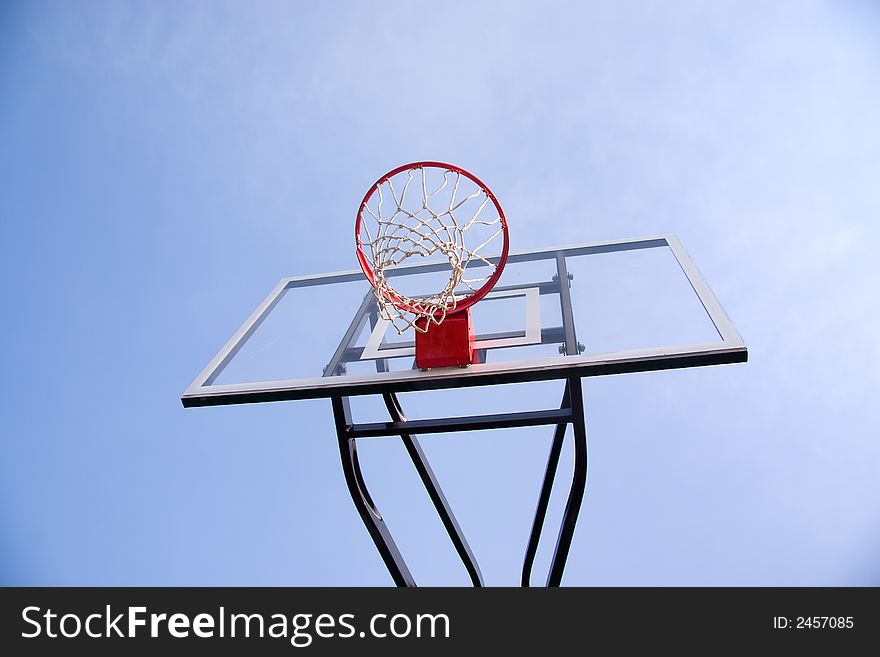 Basketball hoop & backboard from low camera angle against blue sky