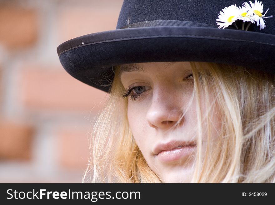Portrait of the beautiful girl in a hat on a background of an old brick wall. Portrait of the beautiful girl in a hat on a background of an old brick wall