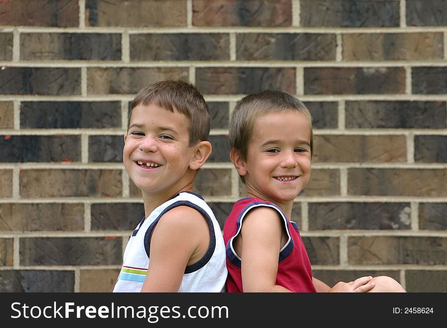 Two Brothers Smiling Against a Brick Wall