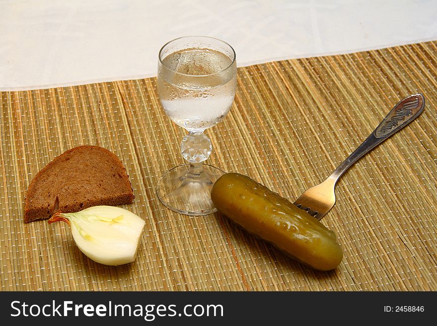 Wineglass of vodka and tradional russian snacks for it - onion, brown bread and sour cucumber. Wineglass of vodka and tradional russian snacks for it - onion, brown bread and sour cucumber