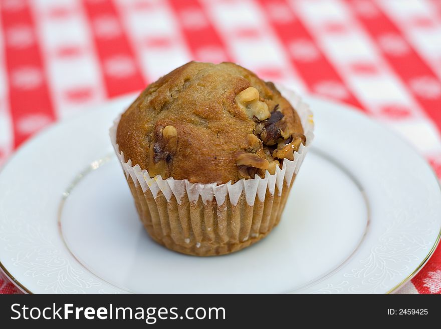 A banana walut muffin on red gingham tablecloth. Shallow depth of field. A banana walut muffin on red gingham tablecloth. Shallow depth of field.