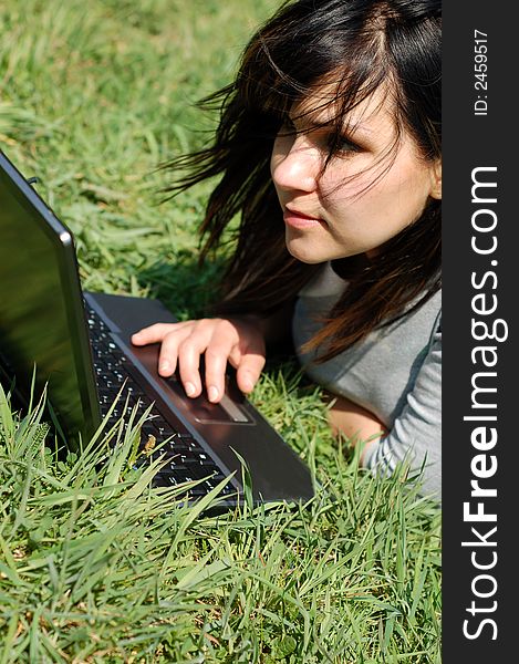 Attractive woman lying with laptop on meadow. Attractive woman lying with laptop on meadow