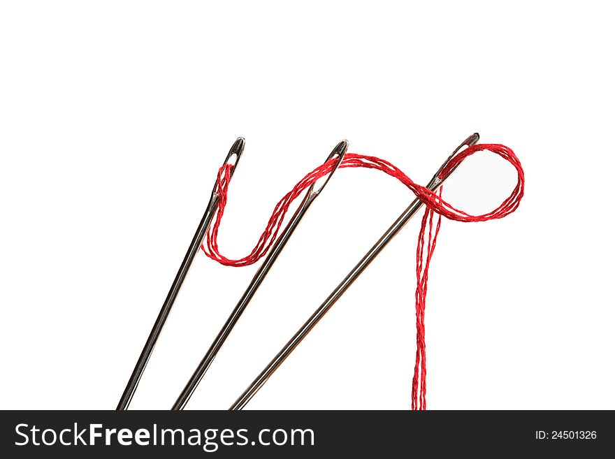 Sewing concept. Closeup of three needles with red thread on white background. Sewing concept. Closeup of three needles with red thread on white background