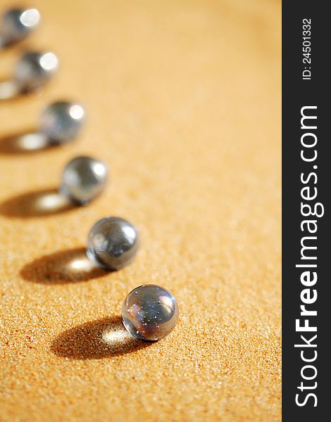 Abstract composition with few blue glass balls in a row on sand surface. Abstract composition with few blue glass balls in a row on sand surface