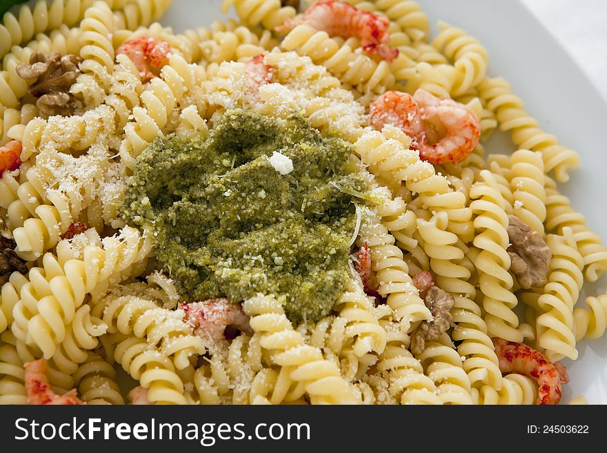 A white dish with pasta with pesto on white background