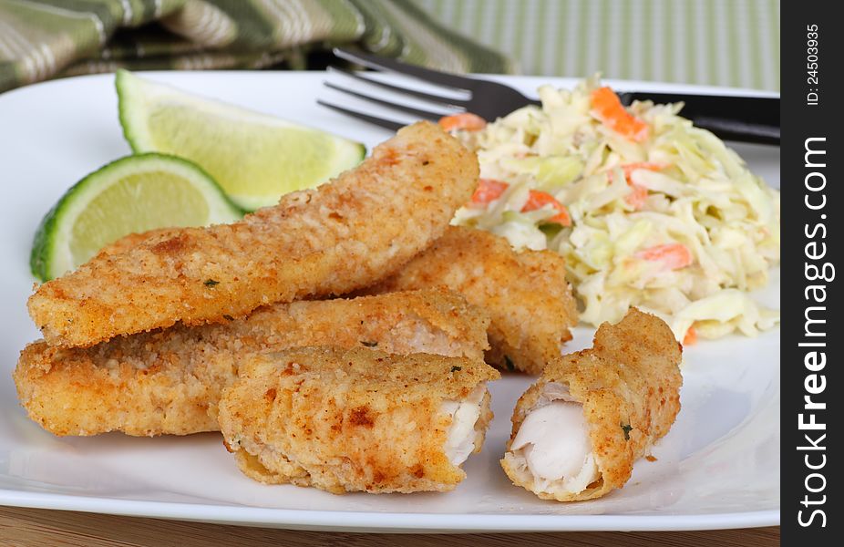 Breaded fish sticks with coleslaw and sliced lime. Breaded fish sticks with coleslaw and sliced lime