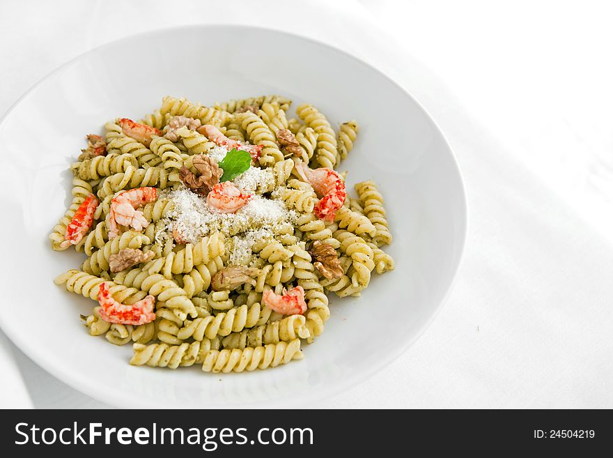 A white dish with pasta with pesto on white table
