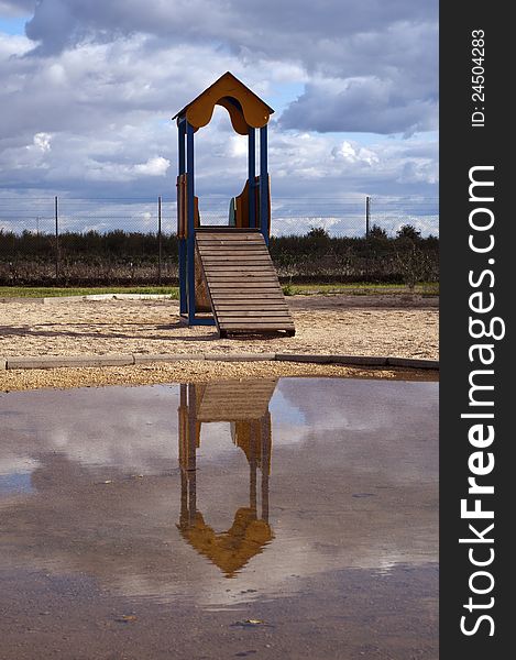 PLAYGROUND with house and cloudy sky in the background