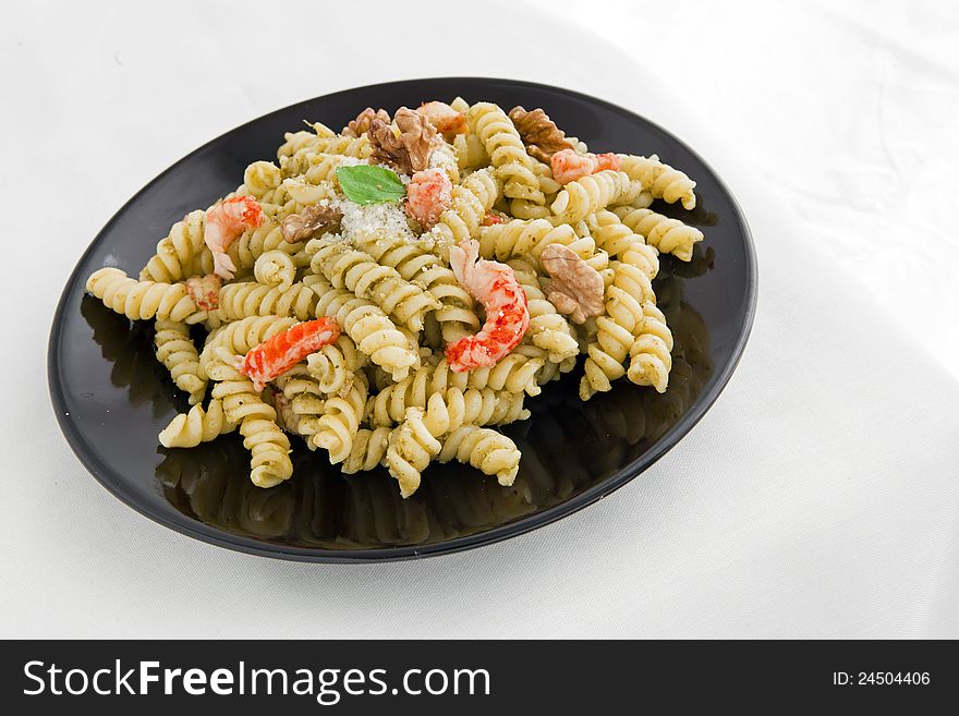 A black dish with pasta with pesto on white table