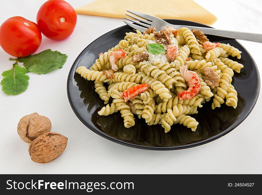 A black dish with pasta with pesto on white table