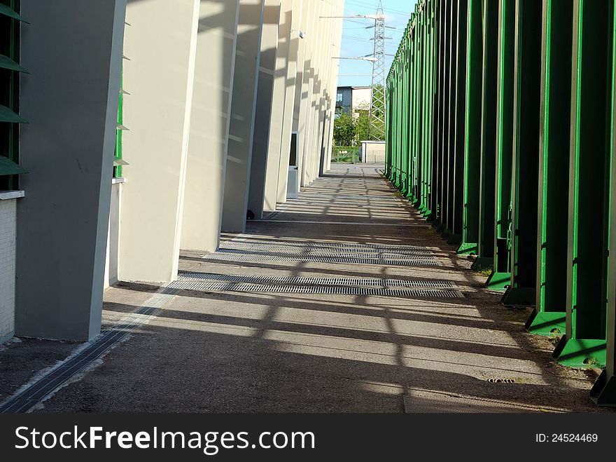 Shady path with a wall and green pipes