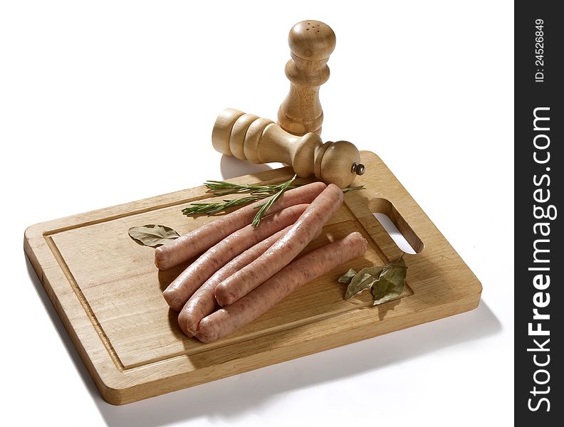 Some raw bavarian sausages on the wooden board with rosemary and bay leaf