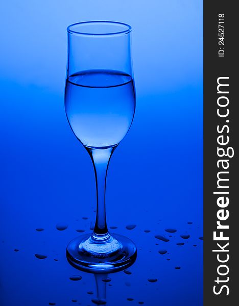 Transparent wine glass filled with water on blue. Transparent wine glass filled with water on blue