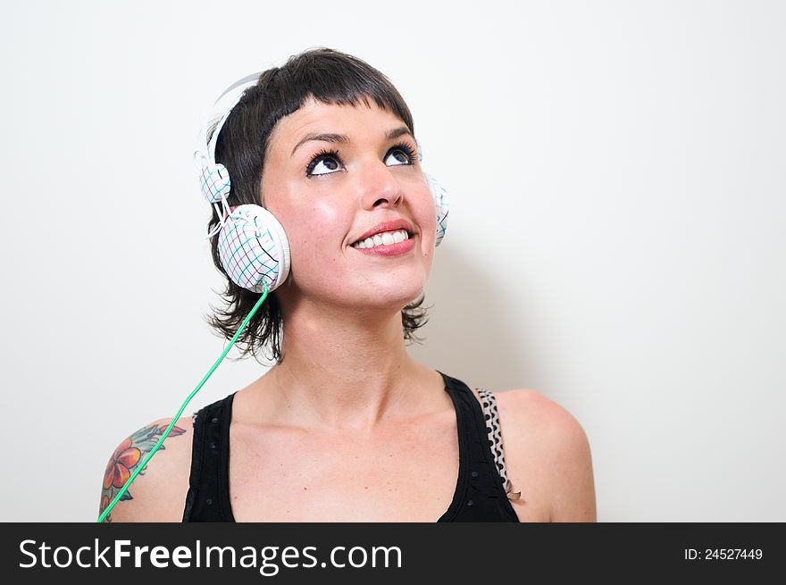 Cute young woman with headphones listening to the music with white background. Cute young woman with headphones listening to the music with white background