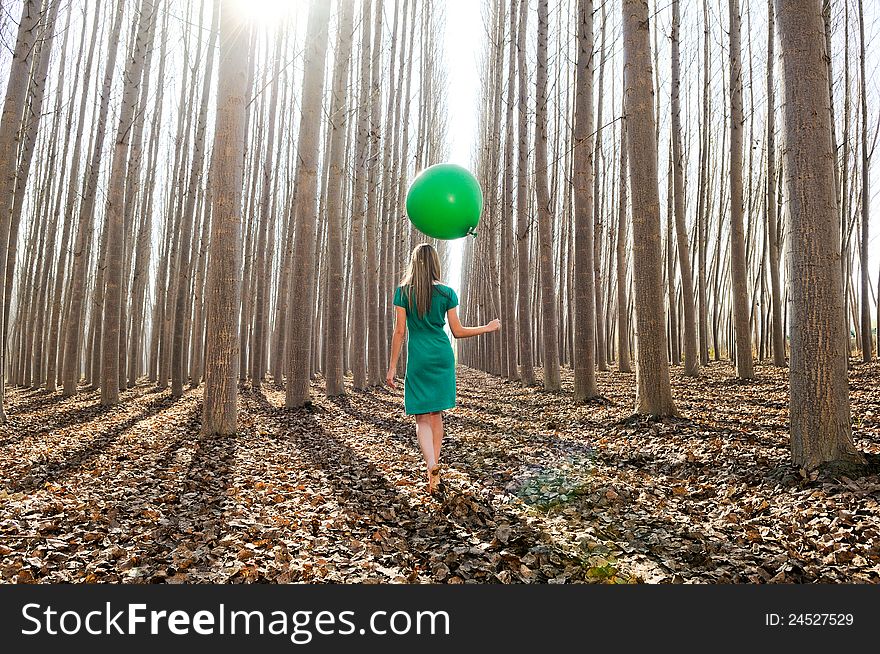 Beautiful blonde girl, dressed in green, walking into the forest. Beautiful blonde girl, dressed in green, walking into the forest