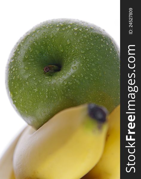 Close up of green apple on top of bananas on white. Close up of green apple on top of bananas on white