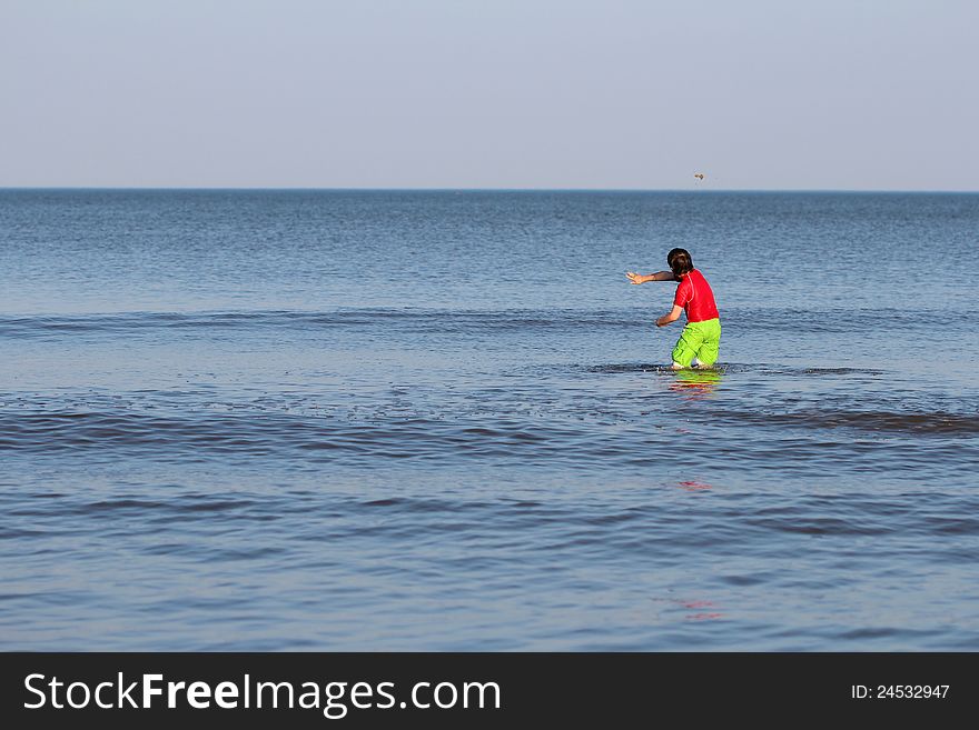 Boy throwing sand while standing in the ocean. Boy throwing sand while standing in the ocean.