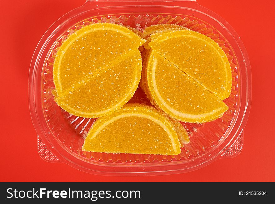 Fruit candy in the form of lemon segments on red background