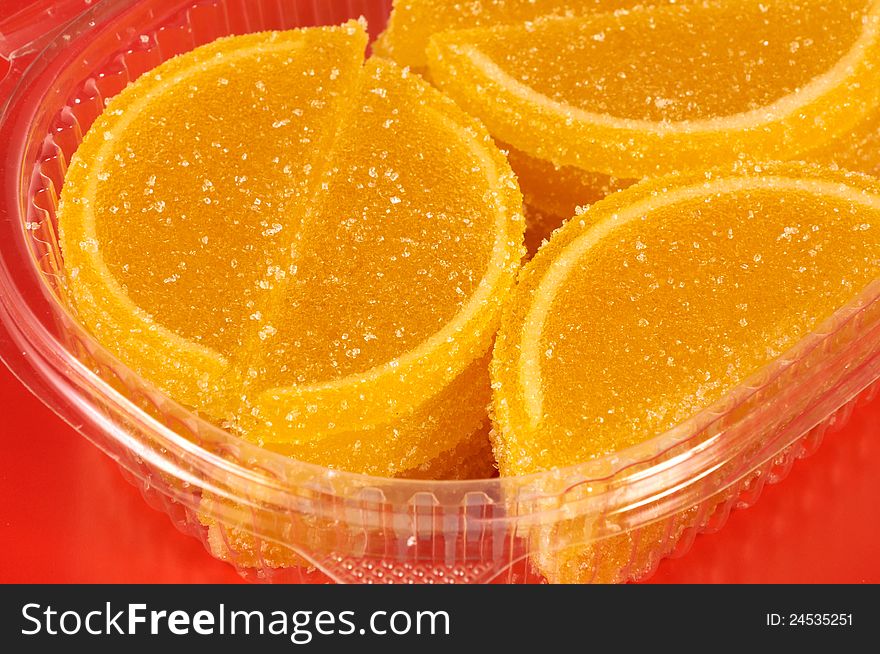 Fruit candy in the form of lemon segments on red background close up