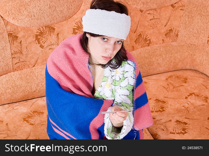 Girl thermometer on the couch wrapped in a blanket