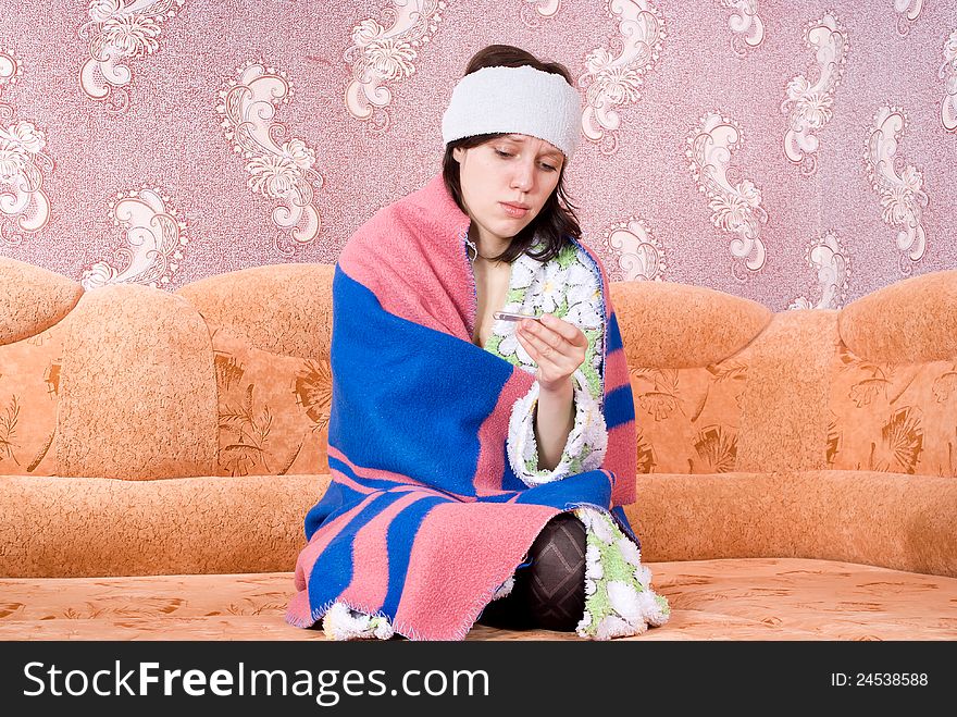 Sick girl thermometer in a bathrobe on the couch. Sick girl thermometer in a bathrobe on the couch