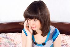 Girl Talking On The Phone While Sitting On The Bed Stock Photo