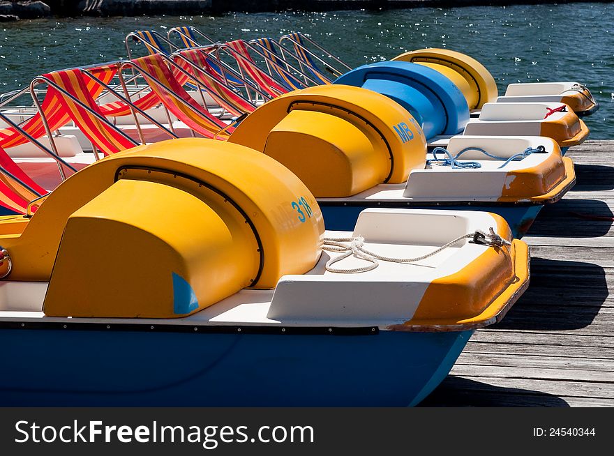 Row of colorful pedal boats on the lake shore