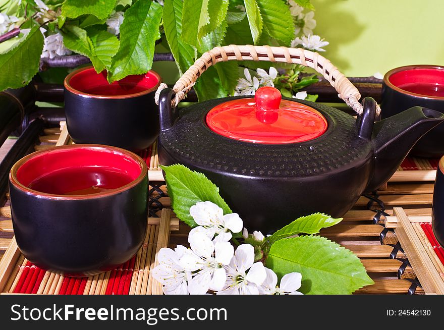 Green tea in a ceramic cup, ceramic teapot, Sakura, chery