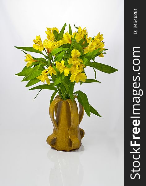 Bunch of flowers in a handmade vase on a white background. Bunch of flowers in a handmade vase on a white background