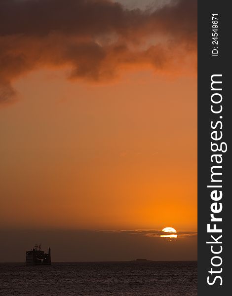 Sunrise over the sea with a ferry at the horizon