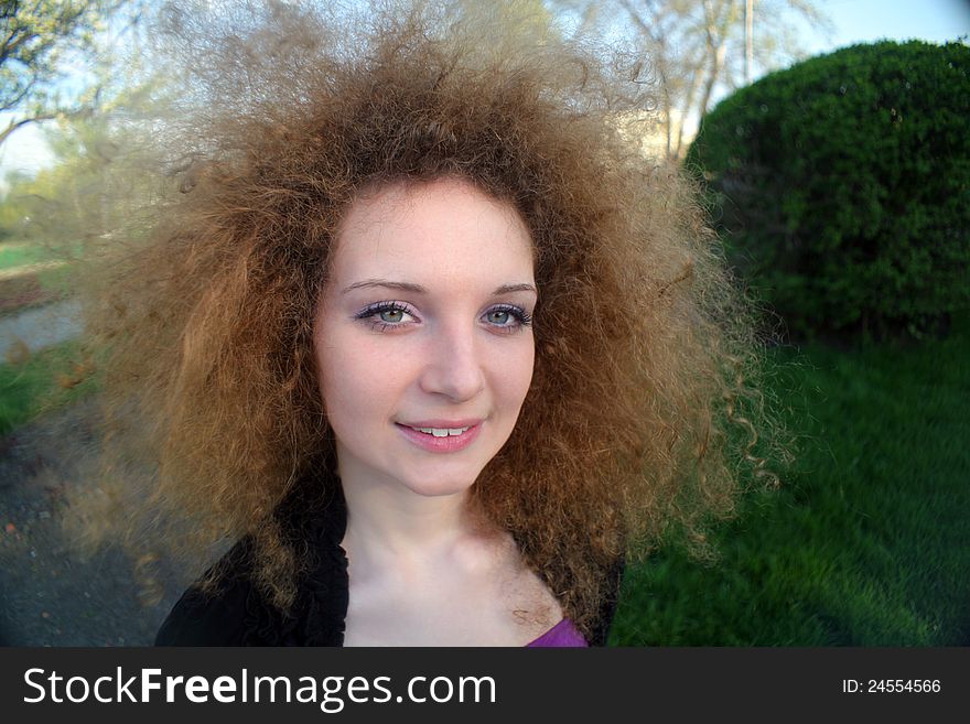 Portrait of a cute curly girl in the park