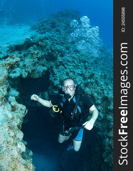 Man scuba diver swims out of canyon in Red sea, Dahab