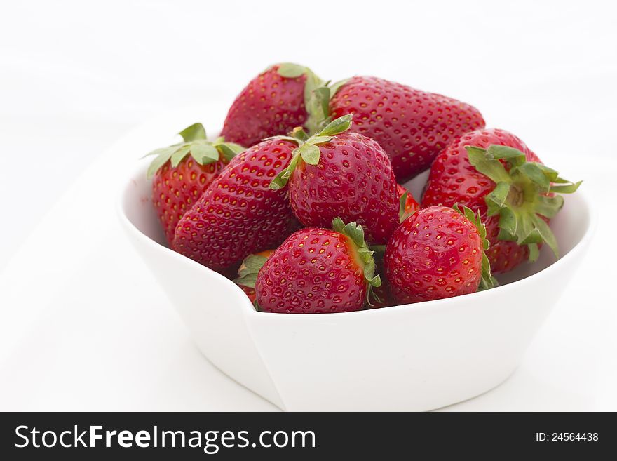 White bowl filled with fresh strawberries. White background.