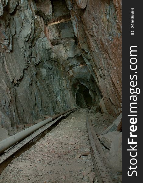 Antique wooden rails lead deep into the depths of this abandoned mine. Randomly spaced wood logs support the rock above. Antique wooden rails lead deep into the depths of this abandoned mine. Randomly spaced wood logs support the rock above.