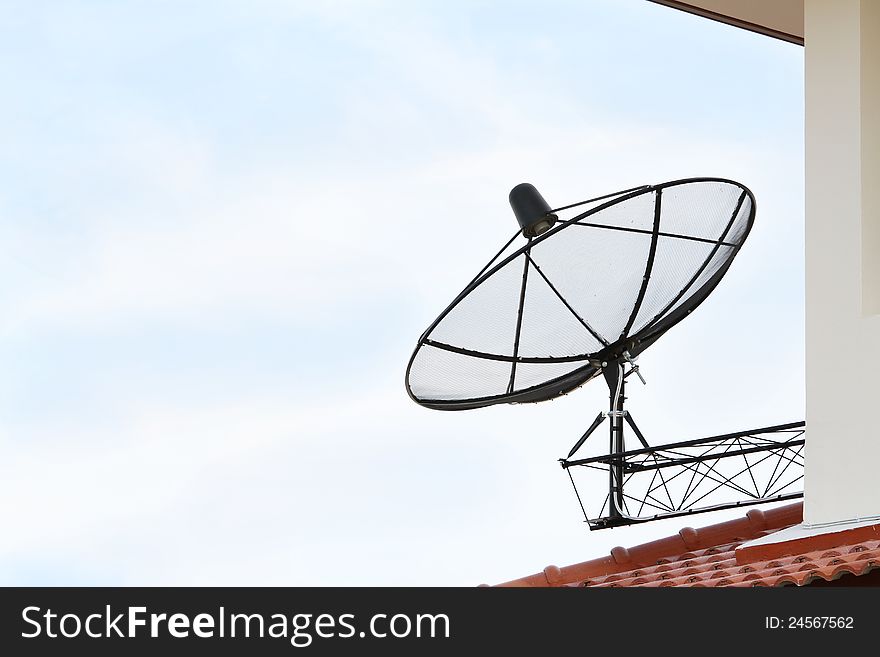 Black satellite dish antenna on blue sky background