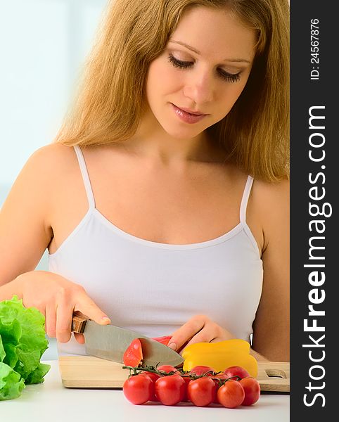 Beautiful young woman, a housewife preparing dinner vegetable salad in the kitchen at home