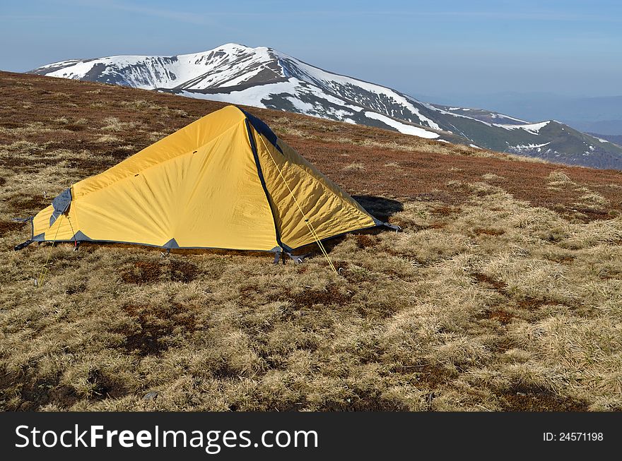 Yellow tent upon snowy spring carpathian ridges. Yellow tent upon snowy spring carpathian ridges