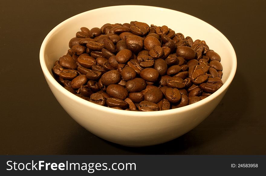 A white bowl filled with coffee beans. A white bowl filled with coffee beans