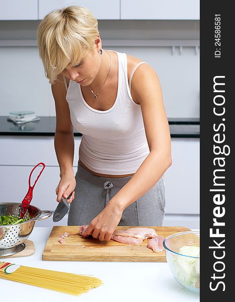 Pretty blond girl in the kitchen making pasta