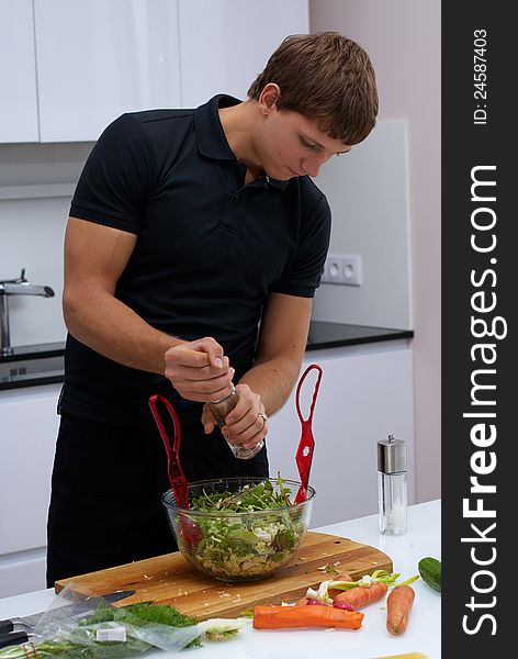 Handsome young man making his breakfast in the kitchen at home