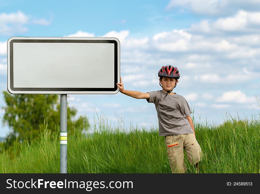 Boy cyclist leaning on blank sign