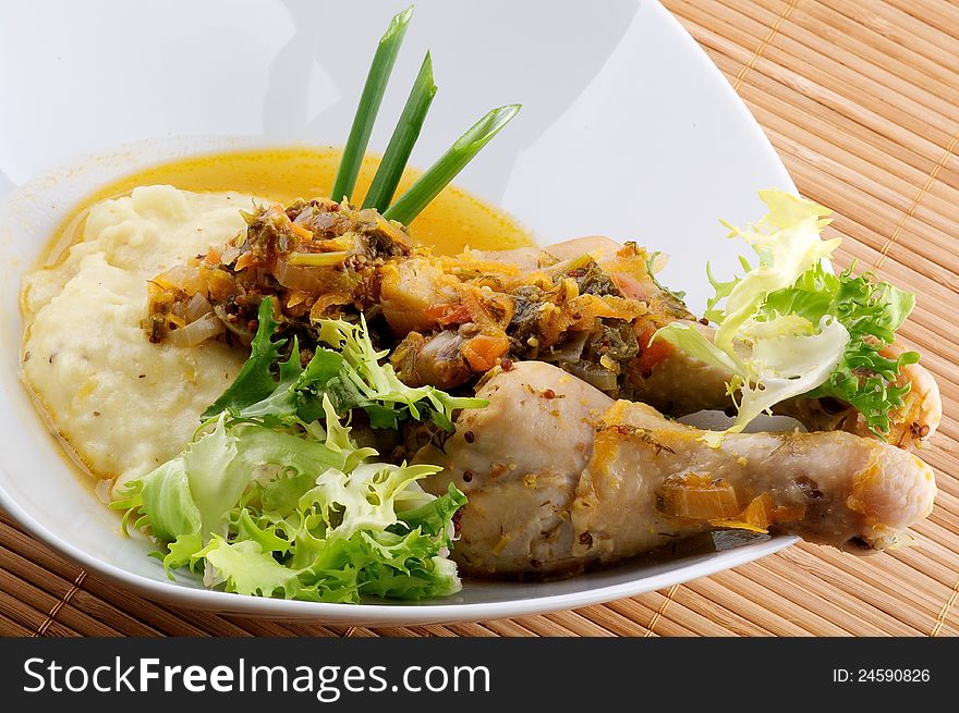 Roasted chicken legs with mashed potatoes, vegetables saute and greens close up on wooden background