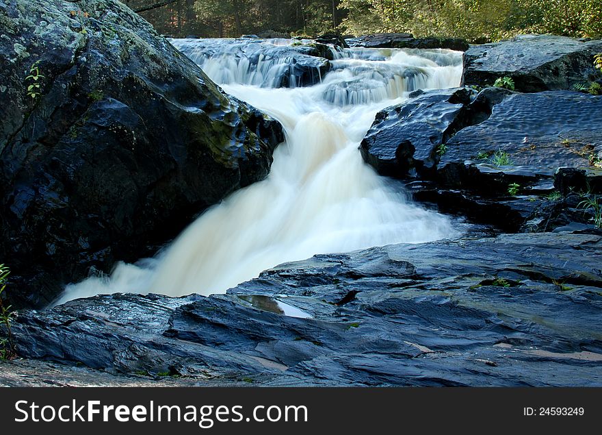 Water fall over large Black Slate Rocks in a creek in the Forest. Water fall over large Black Slate Rocks in a creek in the Forest