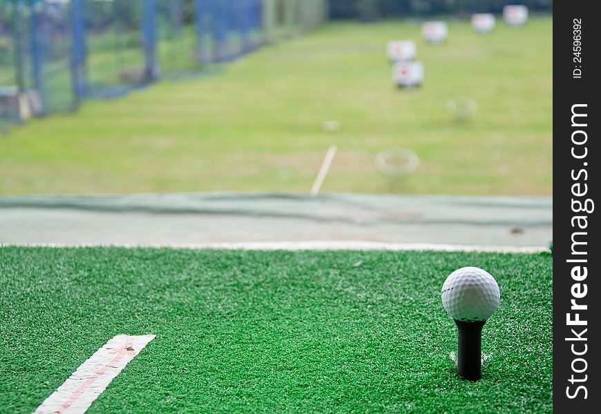 Golf ball on black tee with green grass. Golf ball on black tee with green grass