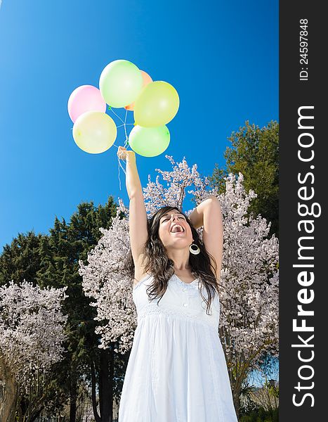 Young beautiful woman playing with colorful balloons, smiling and celebrating love and life in a spring scene. Young beautiful woman playing with colorful balloons, smiling and celebrating love and life in a spring scene.