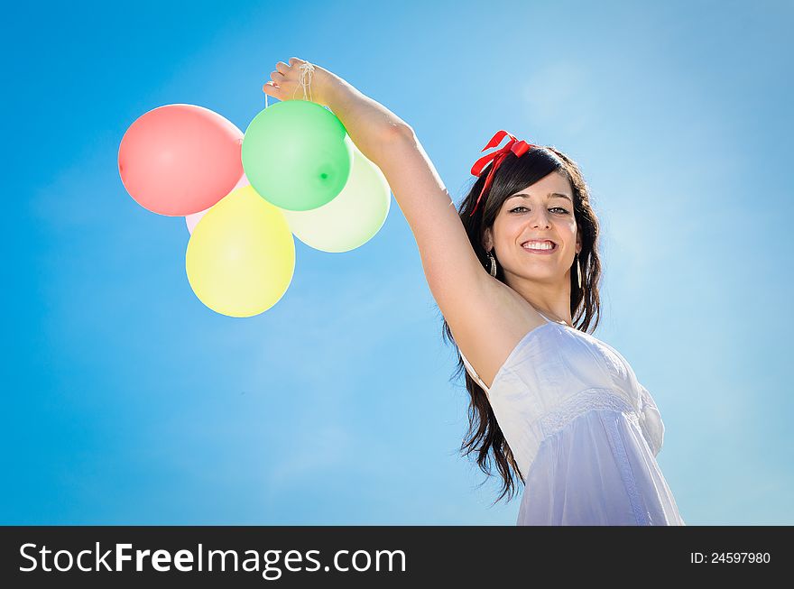 Beautiful brunette woman shows her happiness playing and having fun with colorful balloons. Beautiful brunette woman shows her happiness playing and having fun with colorful balloons.