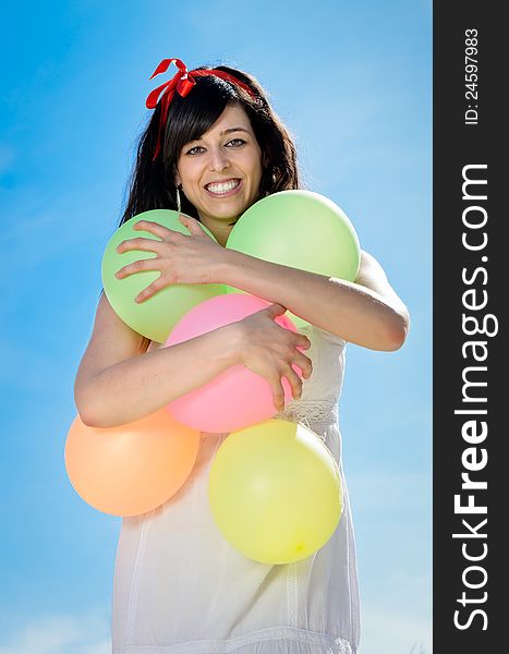 Beautiful brunette woman shows her happiness and love playing and having fun with colorful balloons. She is hugging the balloons. Beautiful brunette woman shows her happiness and love playing and having fun with colorful balloons. She is hugging the balloons.