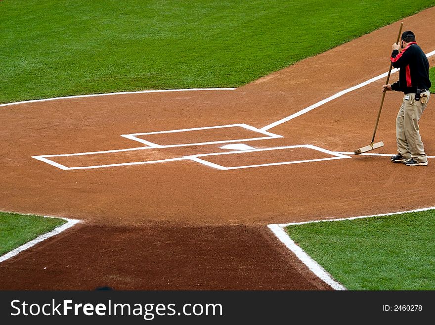 A groundskeeper preparing the home plate area before a baseball game. A groundskeeper preparing the home plate area before a baseball game.